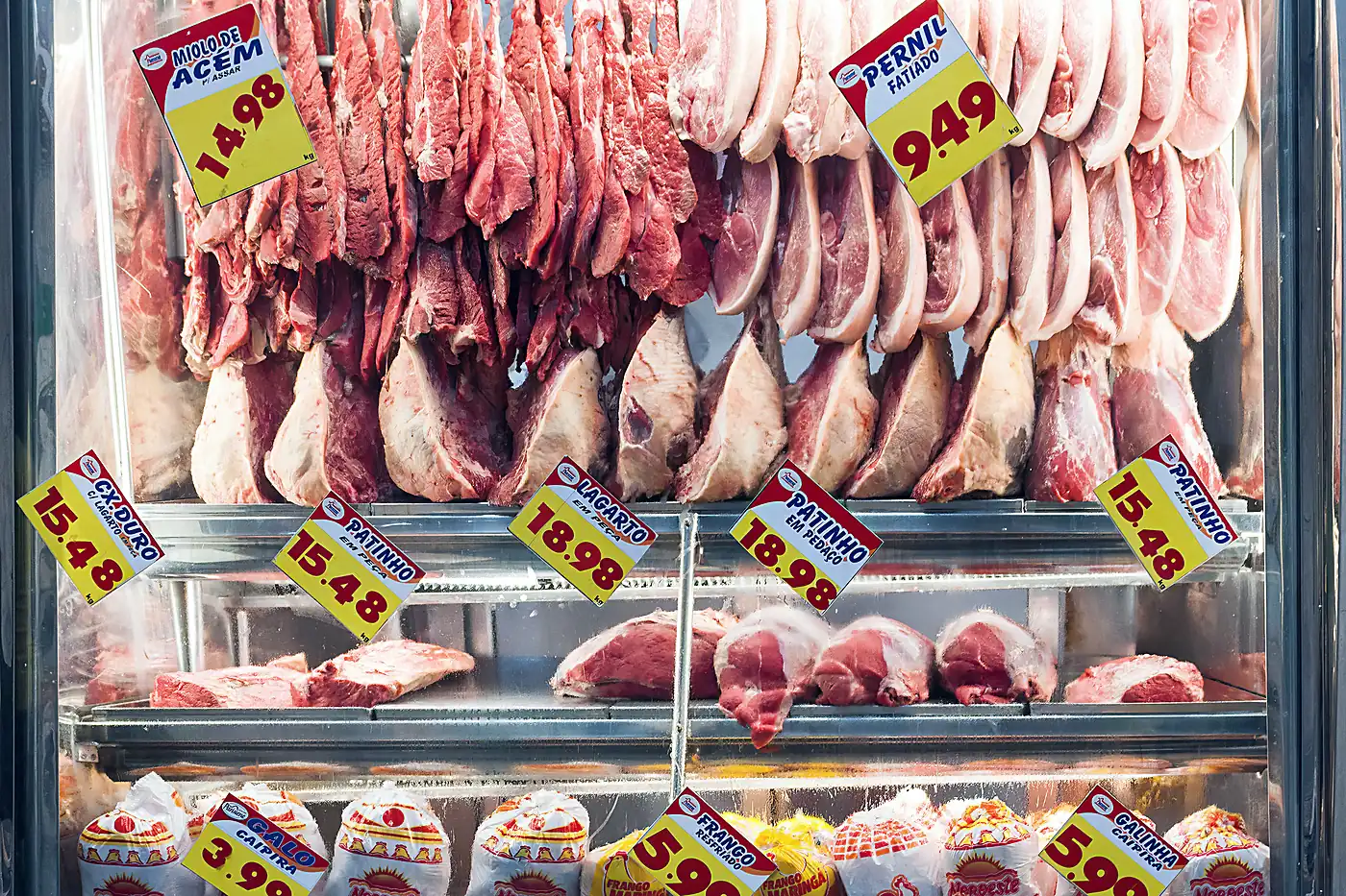 Vitrine de açougue com cortes de carne e etiquetas de preço em reais